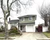 Split level home with a gate, a shingled roof, driveway, brick siding, and a garage Split level home with a gate, a shingled roof, driveway, brick siding, and a garage