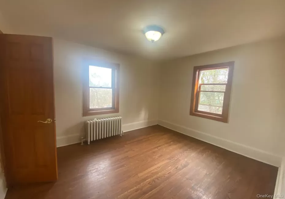 Empty room with baseboards, radiator heating unit, and dark wood-style floors Empty room with baseboards, radiator heating unit, and dark wood-style floors