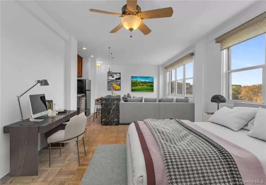 Bedroom featuring light parquet flooring, ceiling fan, and stainless steel refrigerator Bedroom featuring light parquet flooring, ceiling fan, and stainless steel refrigerator