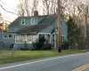 View of front facade featuring a chimney and a shingled roof View of front facade featuring a chimney and a shingled roof