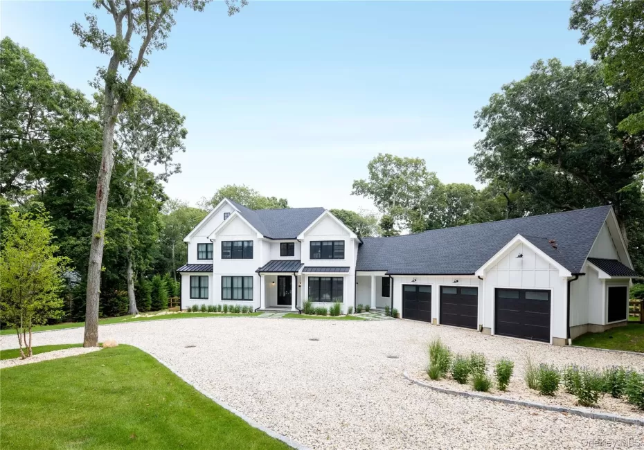 Modern inspired farmhouse with board and batten siding, gravel driveway, an attached garage, a standing seam roof, and roof with shingles Modern inspired farmhouse with board and batten siding, gravel driveway, an attached garage, a standing seam roof, and roof with shingles