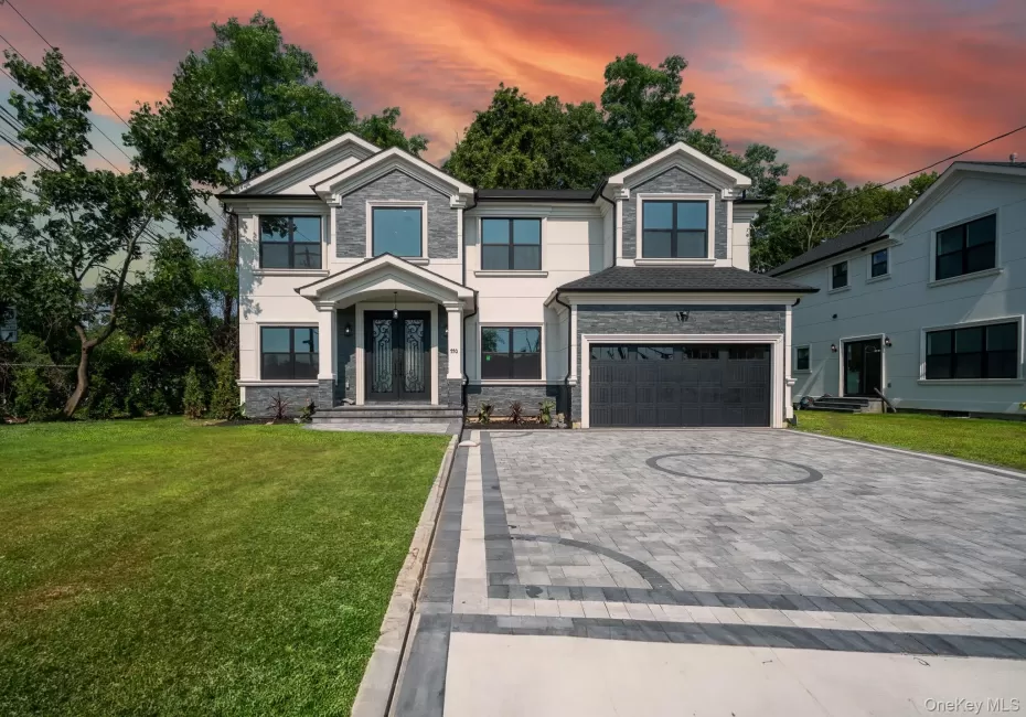 View of front facade featuring decorative driveway, an attached garage, stone siding, and a yard View of front facade featuring decorative driveway, an attached garage, stone siding, and a yard