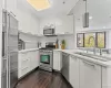 Kitchen featuring white cabinets, appliances with stainless steel finishes, modern cabinets, pendant lighting, and dark wood-style floors Kitchen featuring white cabinets, appliances with stainless steel finishes, modern cabinets, pendant lighting, and dark wood-style floors