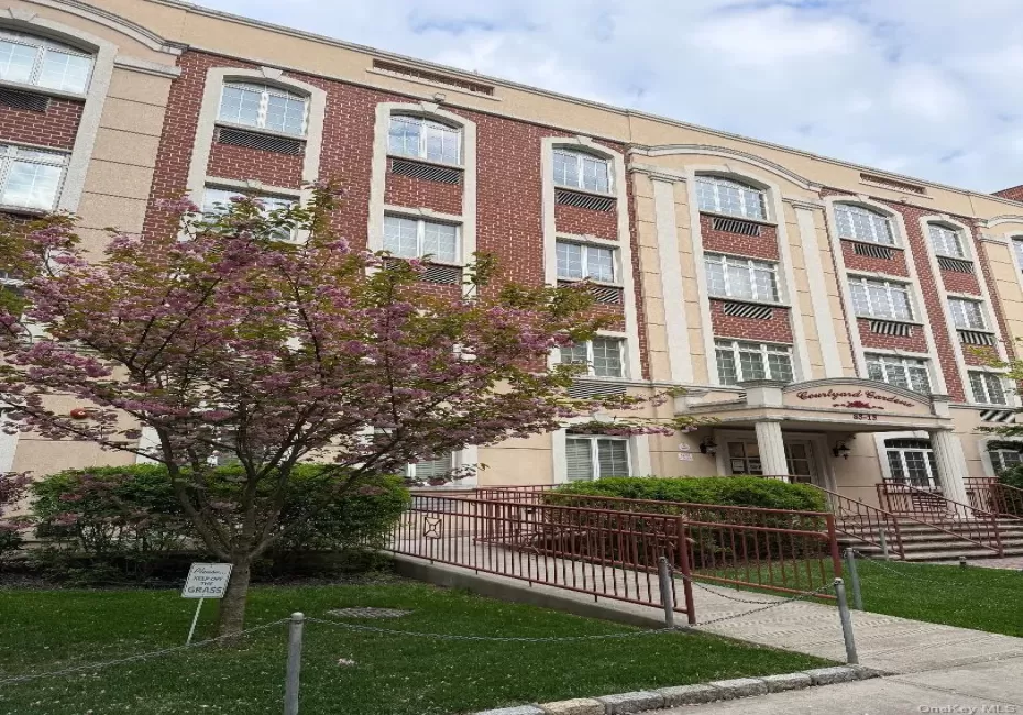 Multi-story building featuring brick and stucco facade, arched windows, and a prominent portico entry Multi-story building featuring brick and stucco facade, arched windows, and a prominent portico entry