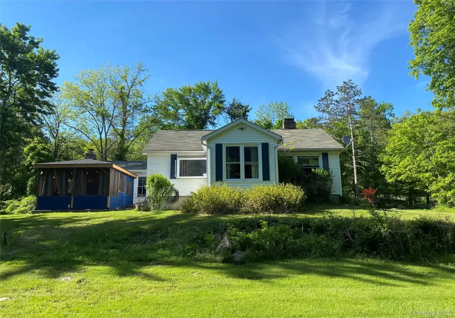 View of front of property featuring a sunroom, a chimney, and a front lawn View of front of property featuring a sunroom, a chimney, and a front lawn