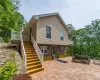 Side view of property with a patio area, stairs, stone siding, and a balcony Side view of property with a patio area, stairs, stone siding, and a balcony