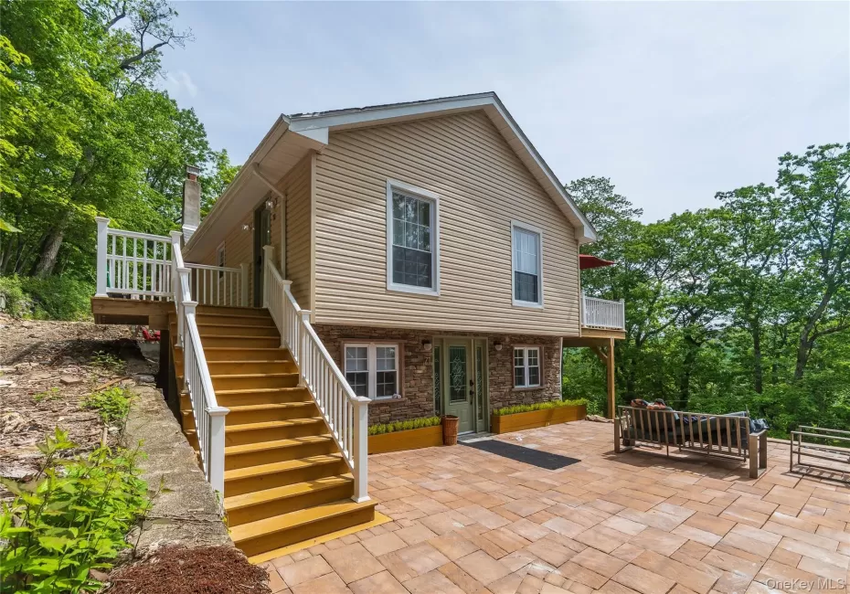 Side view of property with a patio area, stairs, stone siding, and a balcony Side view of property with a patio area, stairs, stone siding, and a balcony