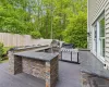 Outdoor kitchen featuring a U-shaped bar with stacked stone facade and dark countertops, a built-in grill, and an additional outdoor cooking appliance Outdoor kitchen featuring a U-shaped bar with stacked stone facade and dark countertops, a built-in grill, and an additional outdoor cooking appliance
