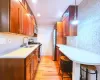 Kitchen featuring brown cabinetry, stainless steel appliances, tasteful backsplash, light wood-type flooring, and a kitchen breakfast bar Kitchen featuring brown cabinetry, stainless steel appliances, tasteful backsplash, light wood-type flooring, and a kitchen breakfast bar