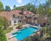 View of pool featuring a balcony, a diving board, a patio area, a water slide, and a pool with connected hot tub View of pool featuring a balcony, a diving board, a patio area, a water slide, and a pool with connected hot tub