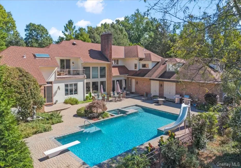 View of pool featuring a balcony, a diving board, a patio area, a water slide, and a pool with connected hot tub View of pool featuring a balcony, a diving board, a patio area, a water slide, and a pool with connected hot tub