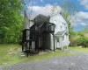 Back of property with stairway, board and batten siding, a wooden deck, roof with shingles, and a chimney Back of property with stairway, board and batten siding, a wooden deck, roof with shingles, and a chimney