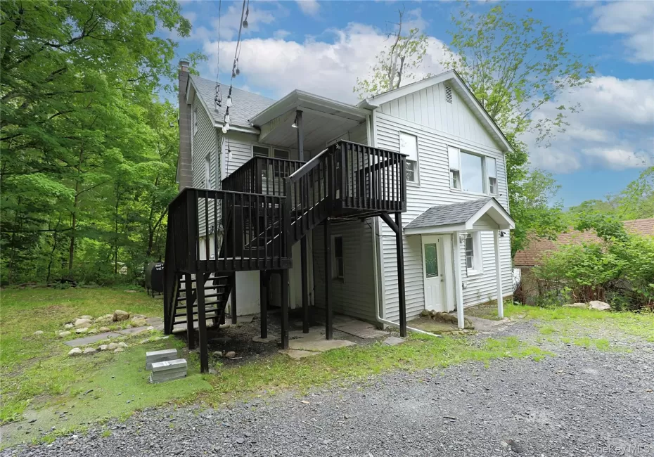 Back of property with stairway, board and batten siding, a wooden deck, roof with shingles, and a chimney Back of property with stairway, board and batten siding, a wooden deck, roof with shingles, and a chimney