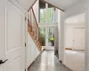 Foyer featuring a grand staircase with wood treads and railings, expansive floor-to-ceiling windows, and a tiled floor Foyer featuring a grand staircase with wood treads and railings, expansive floor-to-ceiling windows, and a tiled floor