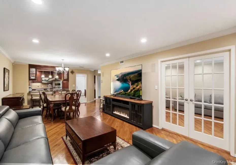 Open-concept living space featuring wood-finish flooring, recessed lighting, and crown molding Open-concept living space featuring wood-finish flooring, recessed lighting, and crown molding
