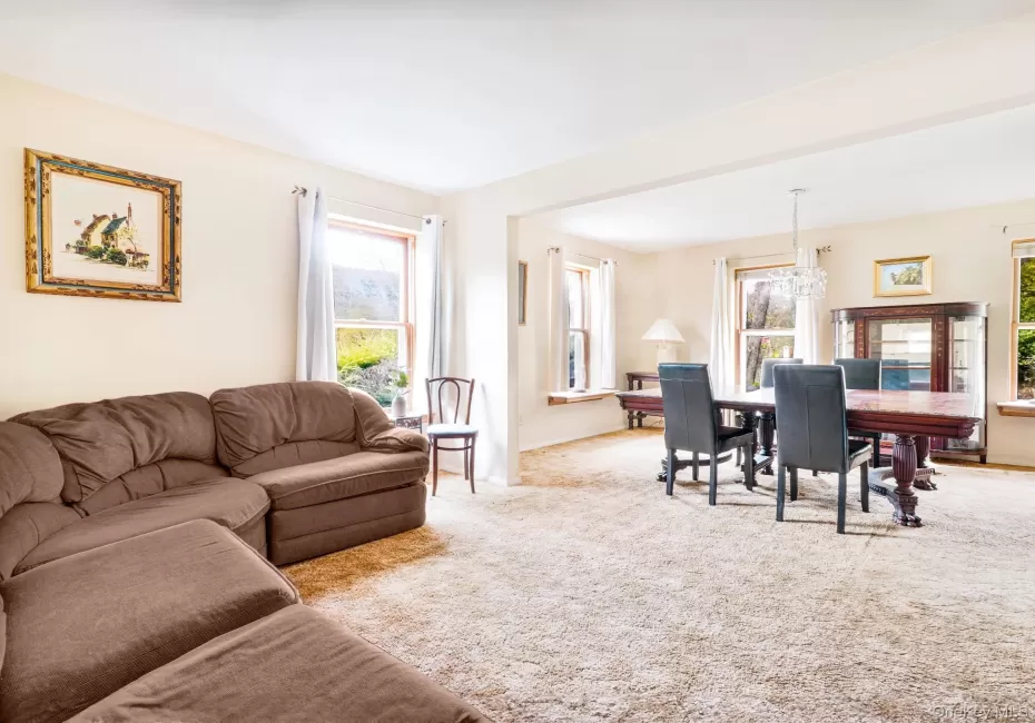 Living area with plenty of natural light, a chandelier, carpet floors, and baseboards Living area with plenty of natural light, a chandelier, carpet floors, and baseboards