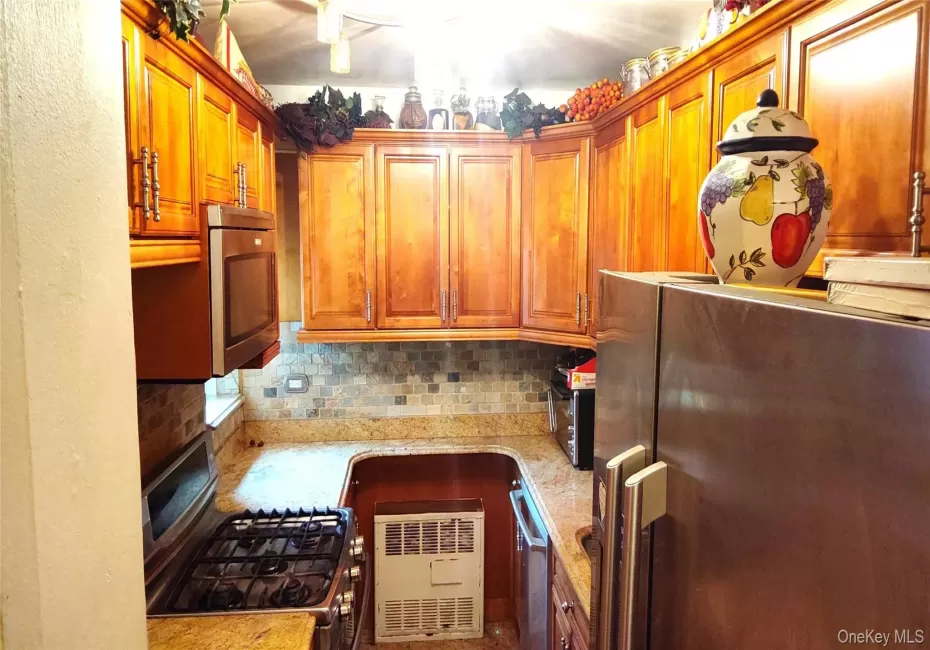 Kitchen featuring wood cabinetry, granite-style countertops, mosaic tile backsplash, stainless steel appliances, and a gas range Kitchen featuring wood cabinetry, granite-style countertops, mosaic tile backsplash, stainless steel appliances, and a gas range