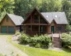 Chalet / cabin featuring covered porch, a garage, stairway, and a shingled roof Chalet / cabin featuring covered porch, a garage, stairway, and a shingled roof