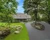 Cape cod-style house with a porch, a front lawn, and curved driveway Cape cod-style house with a porch, a front lawn, and curved driveway