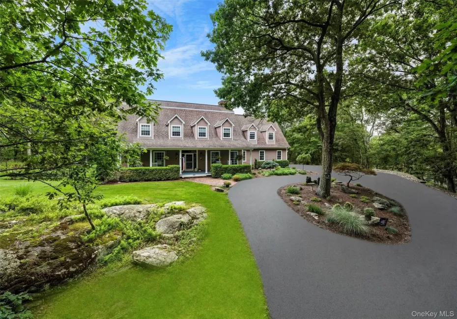 Cape cod-style house with a porch, a front lawn, and curved driveway Cape cod-style house with a porch, a front lawn, and curved driveway
