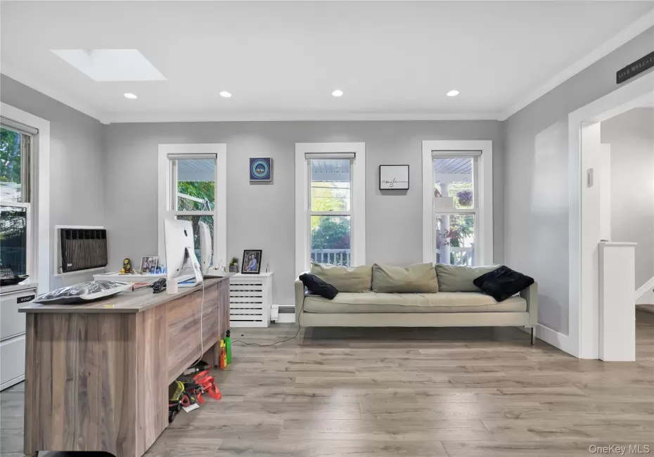 Office space featuring light wood-style floors, crown molding, recessed lighting, a skylight, and baseboard heating Office space featuring light wood-style floors, crown molding, recessed lighting, a skylight, and baseboard heating
