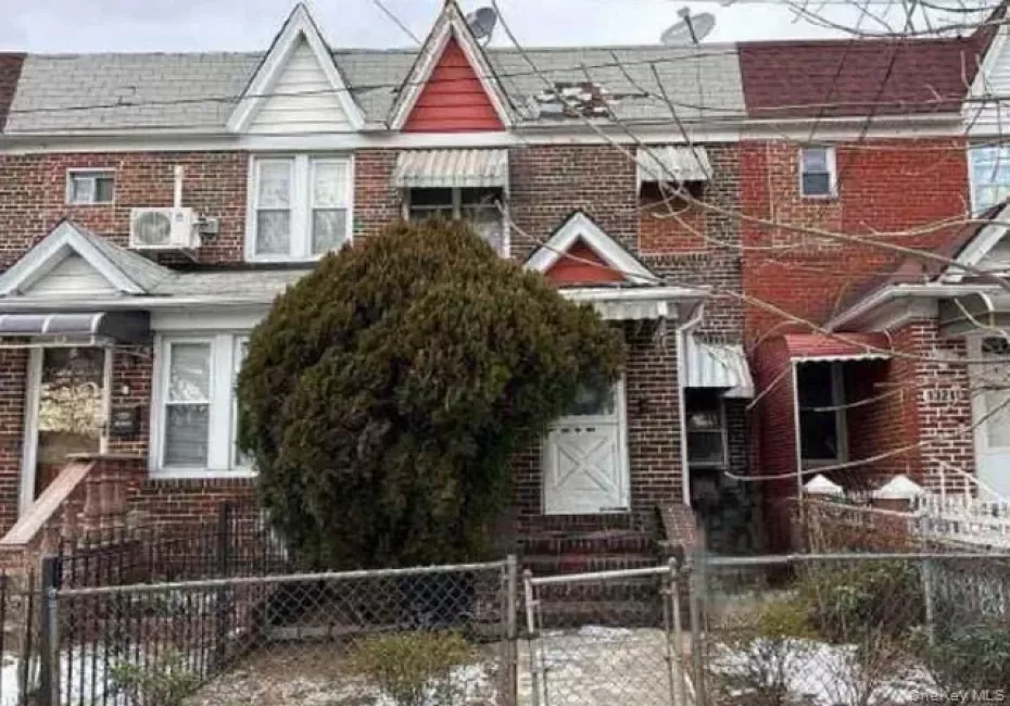 Traditional-style home with a gate, a fenced front yard, brick siding, and roof with shingles Traditional-style home with a gate, a fenced front yard, brick siding, and roof with shingles