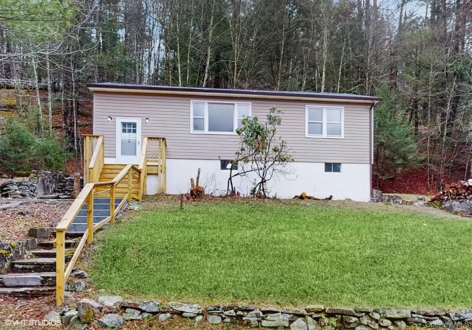 home featuring stairway, a view of trees, and a front yard home featuring stairway, a view of trees, and a front yard
