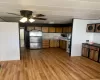 Kitchen with light wood-style flooring, freestanding refrigerator, light countertops, a ceiling fan, and brown cabinets Kitchen with light wood-style flooring, freestanding refrigerator, light countertops, a ceiling fan, and brown cabinets