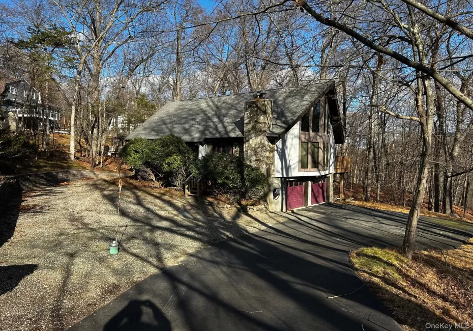 View of side of property with a chimney, driveway, a shingled roof, and a garage View of side of property with a chimney, driveway, a shingled roof, and a garage
