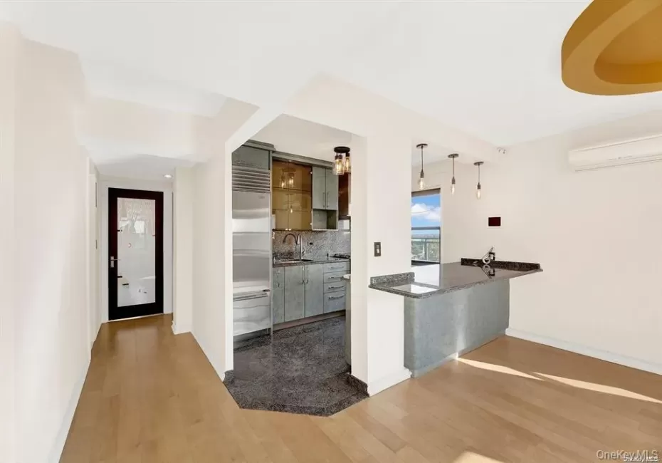 Kitchen with pendant lighting, decorative backsplash, dark wood-style floors, stainless steel built in fridge, and a wall mounted air conditioner Kitchen with pendant lighting, decorative backsplash, dark wood-style floors, stainless steel built in fridge, and a wall mounted air conditioner