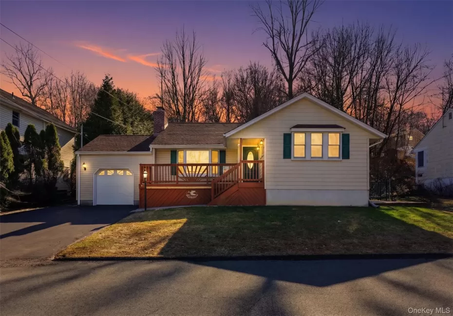 Single story home with a wooden deck, asphalt driveway, a garage, a chimney, and a front yard Single story home with a wooden deck, asphalt driveway, a garage, a chimney, and a front yard