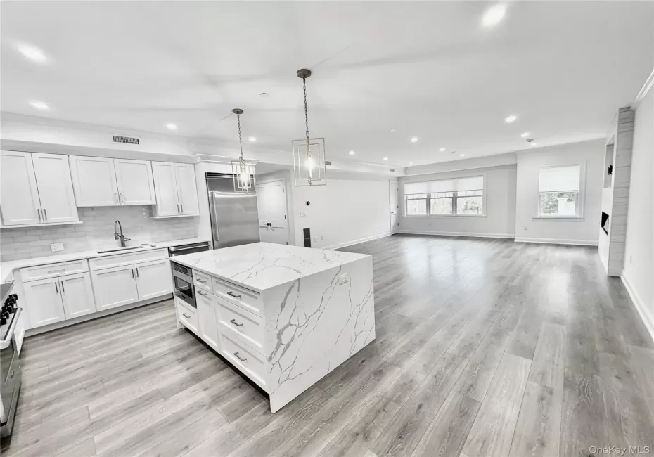 Kitchen with decorative light fixtures, white cabinets, recessed lighting, open floor plan, and a raised ceiling Kitchen with decorative light fixtures, white cabinets, recessed lighting, open floor plan, and a raised ceiling