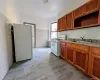 Kitchen featuring white appliances, tile walls, light wood-style flooring, radiator heating unit, and brown cabinets Kitchen featuring white appliances, tile walls, light wood-style flooring, radiator heating unit, and brown cabinets