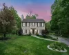 View of front of property featuring a chimney, a yard, and a balcony View of front of property featuring a chimney, a yard, and a balcony