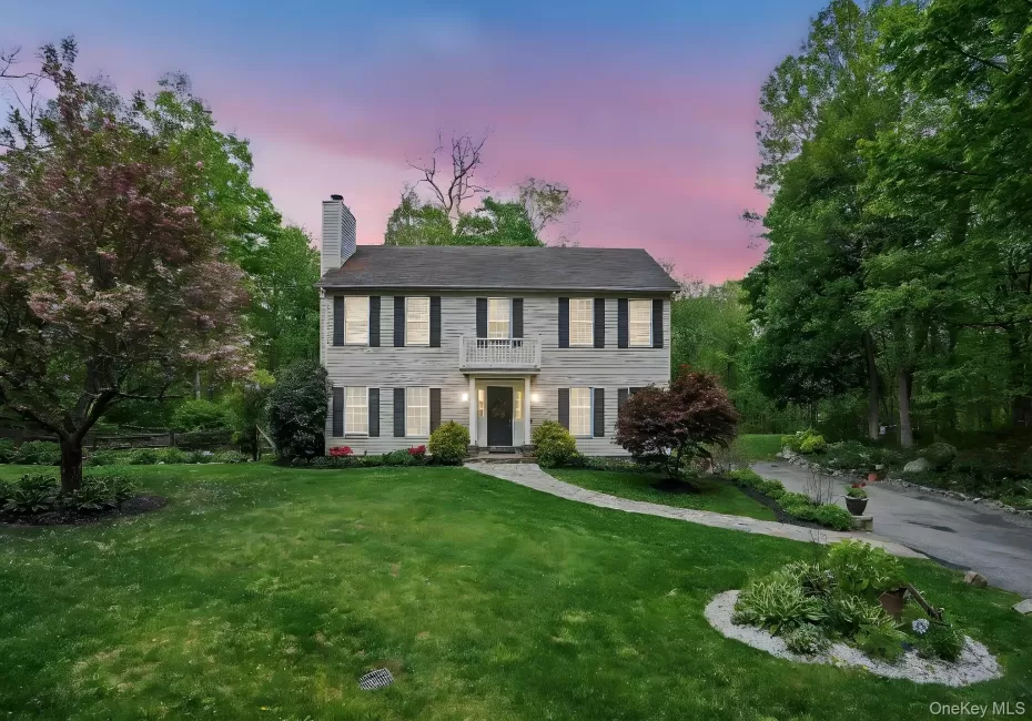 View of front of property featuring a chimney, a yard, and a balcony View of front of property featuring a chimney, a yard, and a balcony