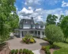 Back of house featuring curved driveway, covered porch, a chimney, and mansard roof Back of house featuring curved driveway, covered porch, a chimney, and mansard roof