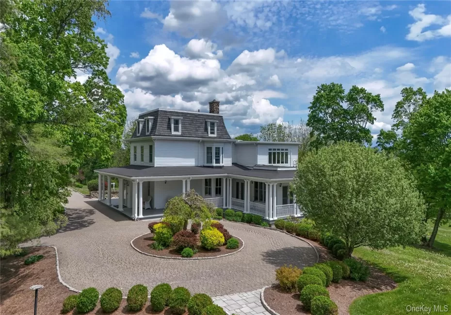 Back of house featuring curved driveway, covered porch, a chimney, and mansard roof Back of house featuring curved driveway, covered porch, a chimney, and mansard roof