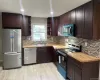 Kitchen with appliances with stainless steel finishes, dark brown cabinets, wooden counters, and recessed lighting Kitchen with appliances with stainless steel finishes, dark brown cabinets, wooden counters, and recessed lighting