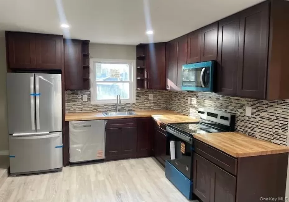 Kitchen with appliances with stainless steel finishes, dark brown cabinets, wooden counters, and recessed lighting Kitchen with appliances with stainless steel finishes, dark brown cabinets, wooden counters, and recessed lighting