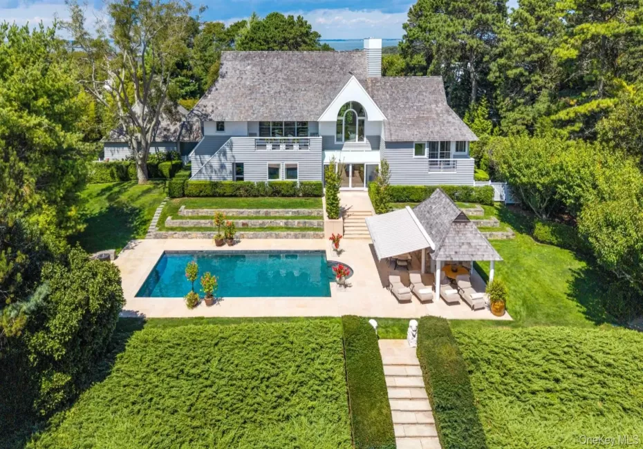 Back of property with a patio area, a balcony, a lawn, a chimney, and an outdoor pool Back of property with a patio area, a balcony, a lawn, a chimney, and an outdoor pool