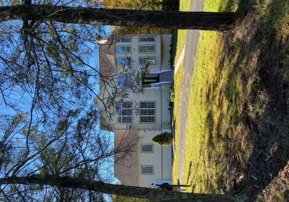 View of front facade with a front lawn, roof with shingles, stucco siding, and a chimney View of front facade with a front lawn, roof with shingles, stucco siding, and a chimney