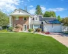 Neoclassical / greek revival house featuring a front yard, solar panels, decorative driveway, and brick siding Neoclassical / greek revival house featuring a front yard, solar panels, decorative driveway, and brick siding