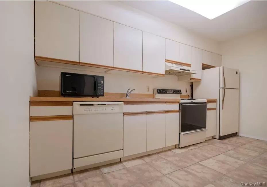 Kitchen with white cabinets, white appliances, under cabinet range hood, and light countertops Kitchen with white cabinets, white appliances, under cabinet range hood, and light countertops