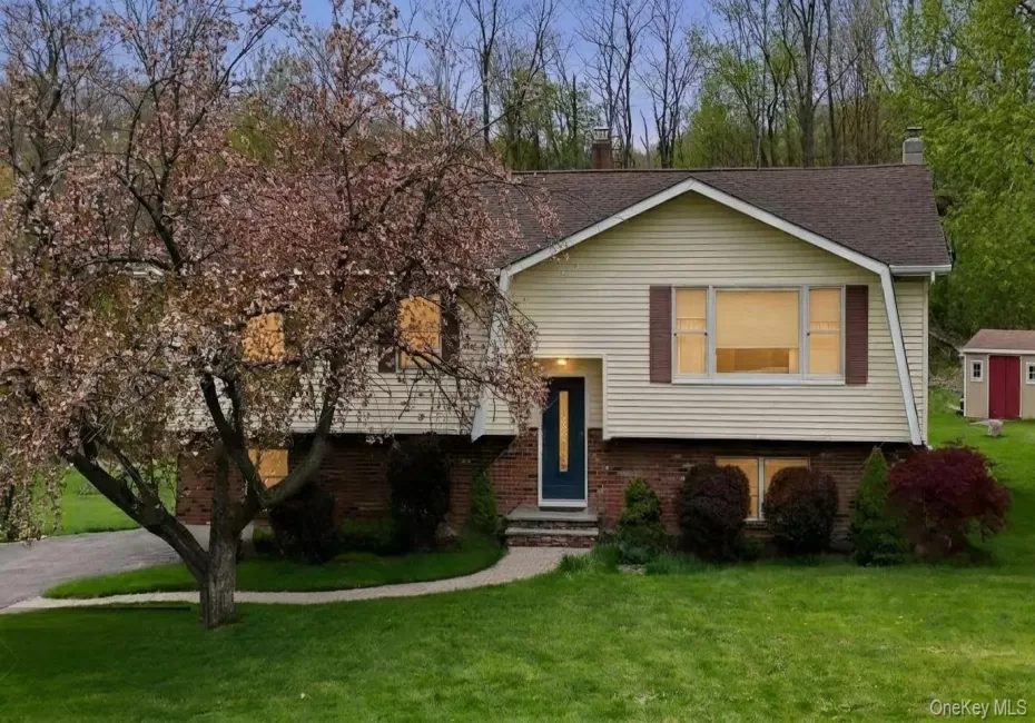 Split-level residence featuring light-colored siding, a dark brown roof, and brick veneer accents Split-level residence featuring light-colored siding, a dark brown roof, and brick veneer accents