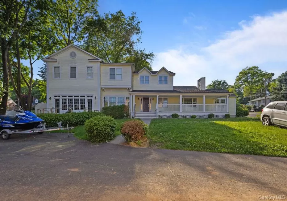 View of front facade featuring a porch, a front lawn, and a chimney View of front facade featuring a porch, a front lawn, and a chimney