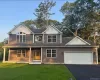 View of front of house with a front lawn, a porch, driveway, a two car garage, and a shingled roof View of front of house with a front lawn, a porch, driveway, a two car garage, and a shingled roof
