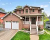 Brick exterior residence featuring a two-car garage, paved driveway, and covered front porch with white balustrades Brick exterior residence featuring a two-car garage, paved driveway, and covered front porch with white balustrades