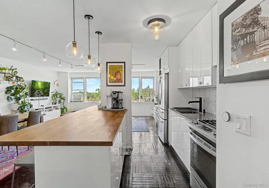 Modern kitchen featuring white high-gloss cabinetry, a black sink, and stainless steel appliances Modern kitchen featuring white high-gloss cabinetry, a black sink, and stainless steel appliances
