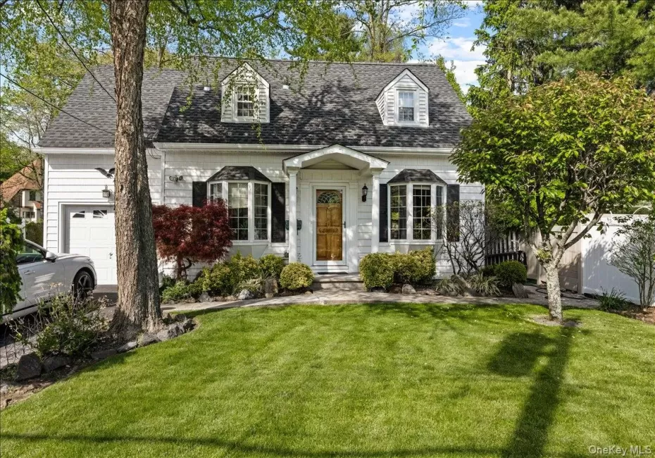 White siding residence featuring a dark shingle roof, dormer windows, and a bay window White siding residence featuring a dark shingle roof, dormer windows, and a bay window