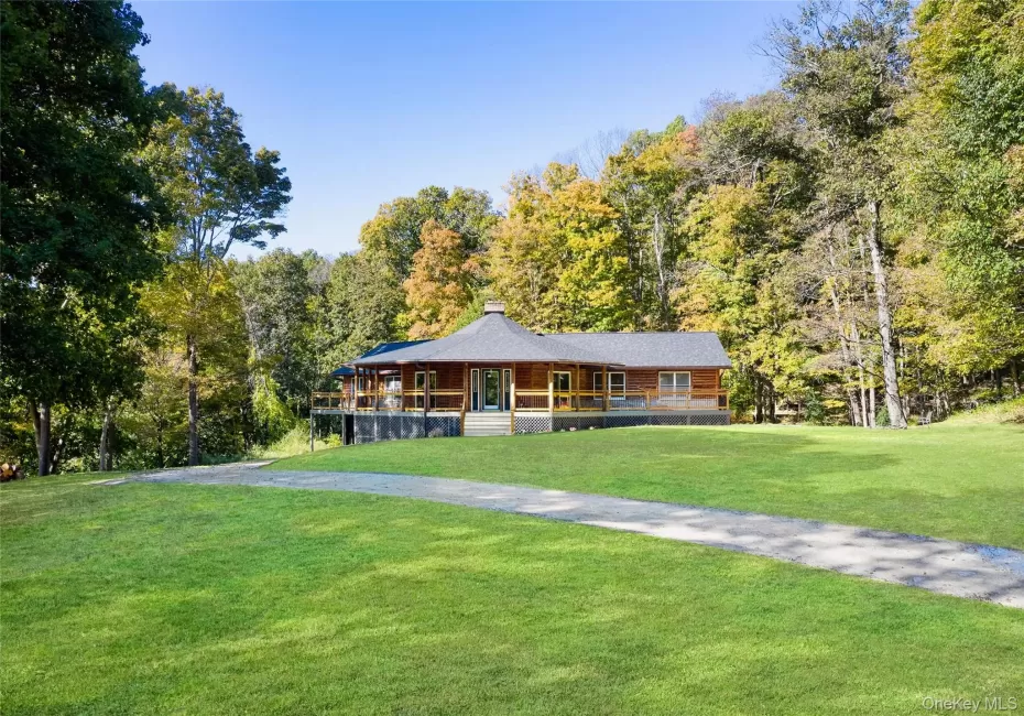 View of front facade featuring a porch, a front yard, a chimney, and a wooded view View of front facade featuring a porch, a front yard, a chimney, and a wooded view